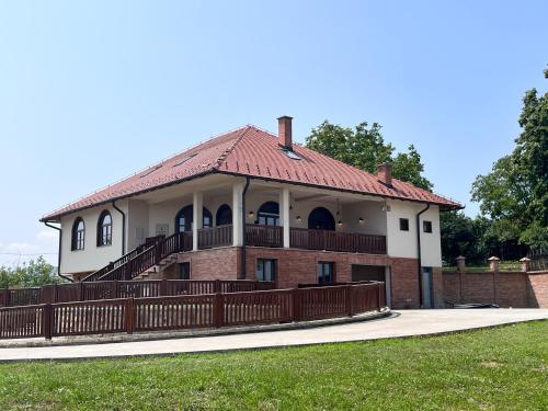 a large brick house with a porch and a fence at Apartmani Vinarije IN in Mionica