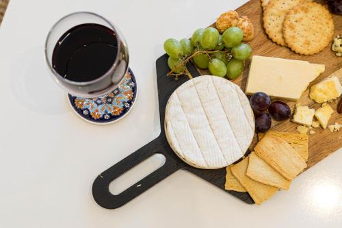 a cutting board with cheese and grapes and a glass of wine at Ocean Breeze - 1 MINUTE FROM THE BEACH - 10 MINUTE FROM BIC - FAST WI-FI - SMART TV in Bournemouth