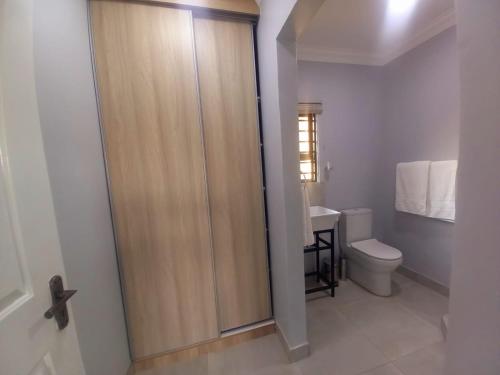 a bathroom with a toilet and a wooden door at REALJOY GUEST SUITES in Centurion