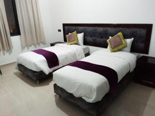 duas camas num quarto de hotel com branco e roxo em HOTEL NASSIM AL-BAHR em Dakhla