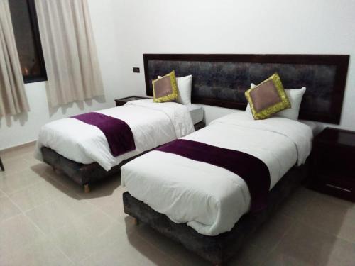 two beds in a hotel room with white and purple at HOTEL NASSIM AL-BAHR in Dakhla