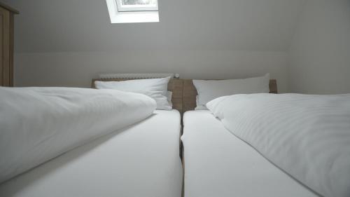 two beds with white sheets and pillows in a room at Fährhaus Hotel in Waldshut-Tiengen