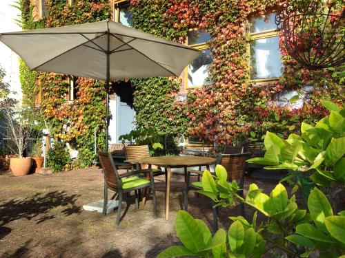 une table et des chaises avec un parasol en face d'un bâtiment dans l'établissement Karl die Große Ferienwohnung, à Dessau