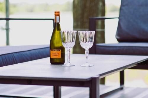 a bottle of wine and two glasses on a table at Wyspa Ciernie - Dom nad jeziorem z sauną i jacuzzi in Ciernie