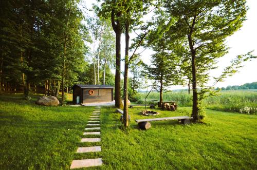 a cabin in the middle of a field with trees at Wyspa Ciernie - Dom nad jeziorem z sauną i jacuzzi in Ciernie