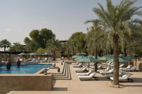 a resort with a pool and lounge chairs and palm trees at Bab Al Shams, A Rare Finds Desert Resort, Dubai in Dubai
