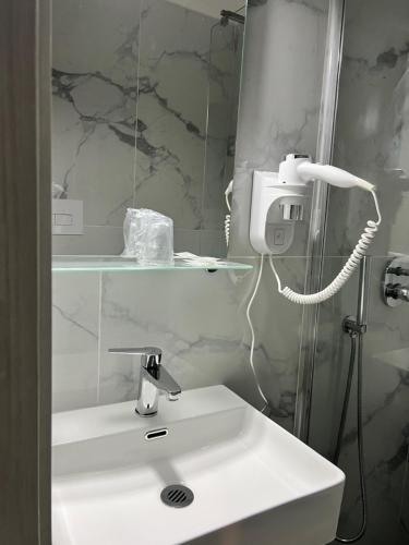 La salle de bains est pourvue d'un lavabo blanc et d'un miroir. dans l'établissement Hotel Sara, à Milan