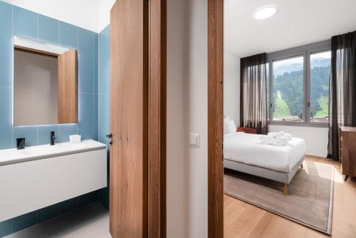 y baño con cama, lavabo y espejo. en Swiss Hotel Apartments - Engelberg, en Engelberg