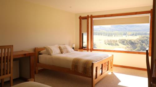 um quarto com uma cama e uma grande janela em Coyhaique River Lodge em Coihaique