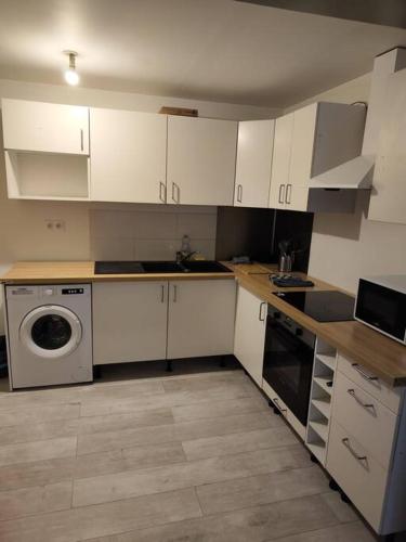 een keuken met witte kasten en een wasmachine bij Jaures F3 duplex 2 chambres wifi in Elbeuf