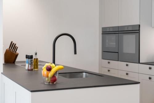 a kitchen counter with a sink and a bowl of fruit at Swiss Hotel Apartments - Engelberg in Engelberg