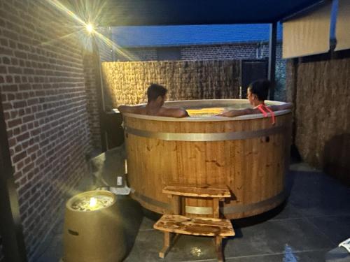 two people in a large wooden tub in a room at GITES LA POMMERAIE MARESCHES in Maresches