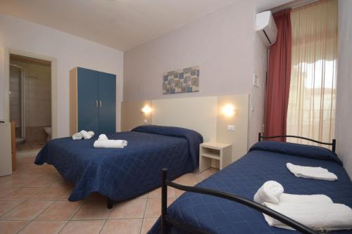 チェゼナーティコにあるHotel Atmosfere Beachの青いシーツとタオルが備わる客室内のベッド2台