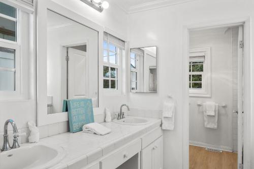 a white bathroom with two sinks and a mirror at By The Sea in San Diego