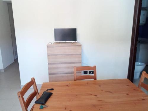 einem Holztisch mit zwei Stühlen und einem TV darüber in der Unterkunft Casa vacanze sul mare in SantʼAlessio Siculo