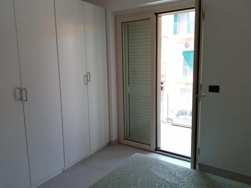 Zimmer mit weißen Schränken und Glasschiebetür in der Unterkunft Casa vacanze sul mare in SantʼAlessio Siculo