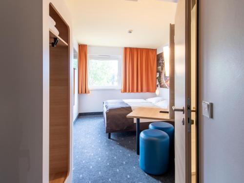 um quarto de hotel com uma cama, uma mesa e uma janela em B&B Hotel Augsburg-Süd em Augsburg