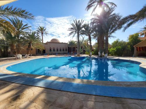 una piscina en un complejo con palmeras en hotel jnane la kasbah 