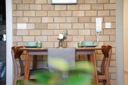 a dining room table with chairs and a brick wall at Nakheel Residence Sabah Alsalem by House living in Kuwait