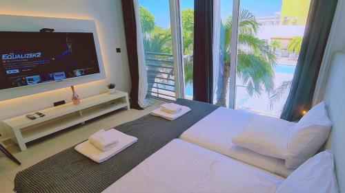 a bedroom with a large white bed and a television at STAY Mezarina Apt 2 in Ayia Napa