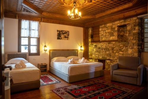 a bedroom with two beds and a chair and a couch at Hotel Kapllani in Berat