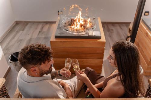 a man and woman drinking wine in front of a fireplace at Legato Spa Suites in Naxos Chora