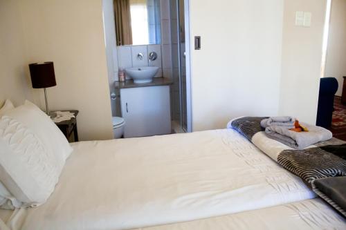 a bedroom with a white bed with a stuffed animal on it at De Oude Yotclub in Oudtshoorn
