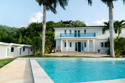 a house with a swimming pool and palm trees at Manati World Point Inn in Manati