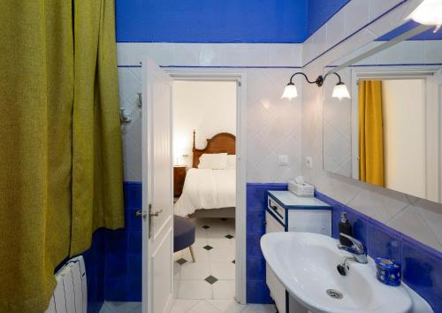 La salle de bains bleue et blanche est pourvue d'un lavabo et d'un miroir. dans l'établissement PALACIO DON CARLOS, à Jerez de la Frontera
