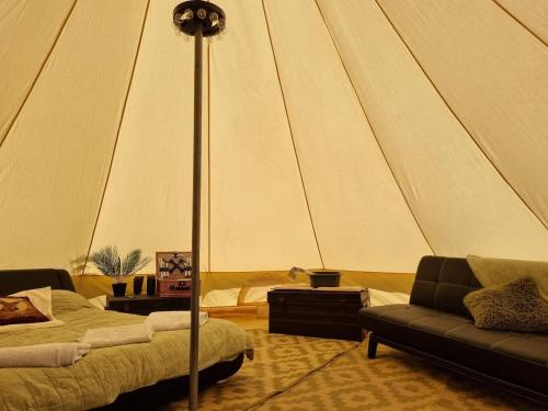 Cette chambre comprend une tente avec un canapé et une table. dans l'établissement Glamping in style Bell tent, à Ifield