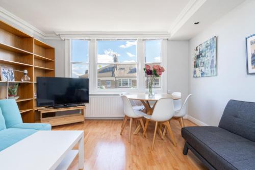 uma sala de estar com uma mesa e uma televisão em ALTIDO Bright apt in West Hampstead em Londres