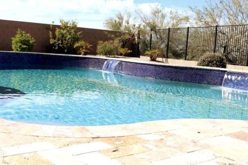 a swimming pool with a waterfall in a yard at Phoenix Home with heated pool, desert views & hot tub in Anthem