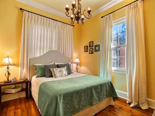 a bedroom with a bed with a chandelier and a window at Coral Cottage in Savannah