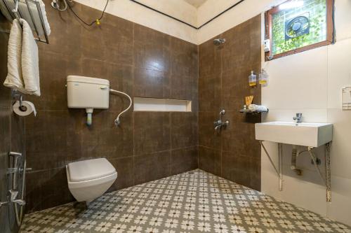 y baño con aseo y lavamanos. en StayVista's Suman Vatika - Pench - Outdoor Pool, Jacuzzi, Rainshower & Terrace, en Khawāsa