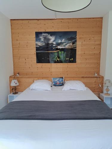 a bedroom with a large bed with a wooden headboard at Hôtel Les Mouflons in Le Mont-Dore