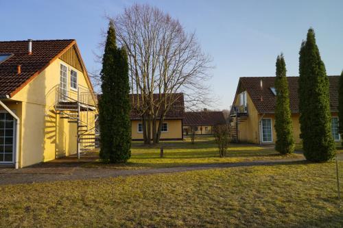 a row of houses in a yard with trees at Ferienpark am Darß - Apartmenthaus 2 in Fuhlendorf