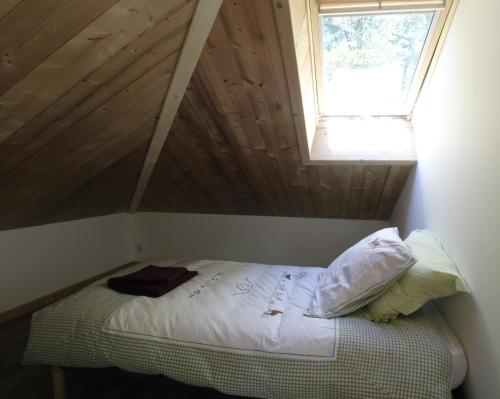 a bed in a room with a roof with a window at Charmant petit chalet individuel in Briançon