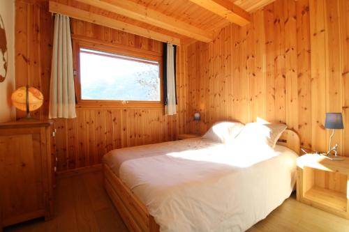 1 dormitorio con 1 cama en una habitación de madera en Charmant petit chalet individuel, en Briançon