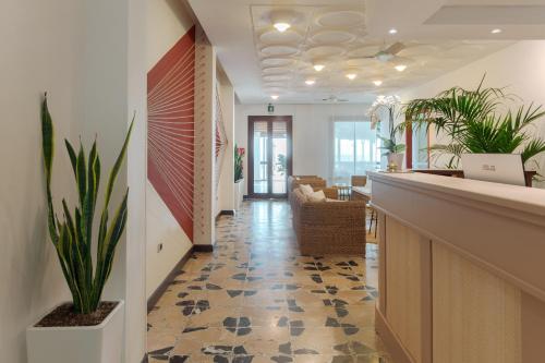un hall de bureau avec un comptoir de réception et des plantes dans l'établissement Hotel da Cesare Maluentu, à Putzu Idu