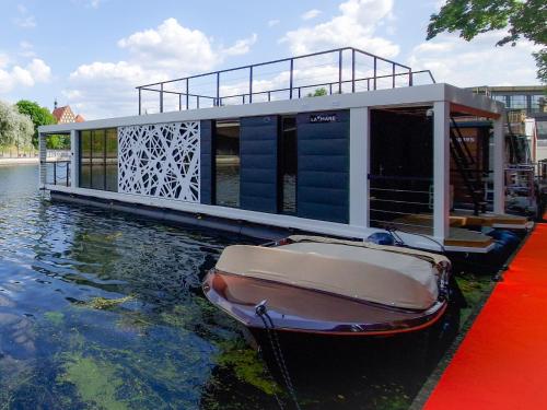 a boat sitting in the water next to a house at Dom na wodzie LaMare Modern 14 in Bydgoszcz