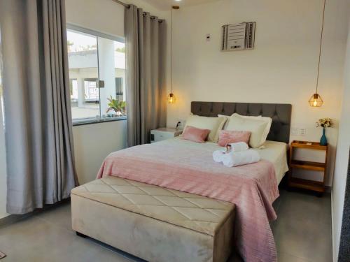 a bedroom with a large bed with pink pillows at CHALÉS GUARAÍPE in Guarapari