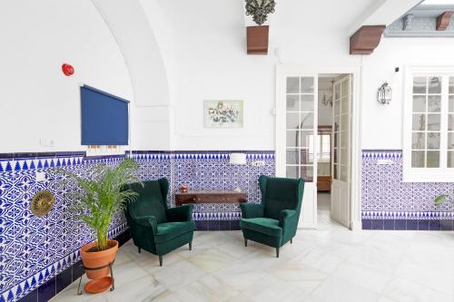 a lobby with blue and white tiles and green chairs at PALACIO DON CARLOS in Jerez de la Frontera