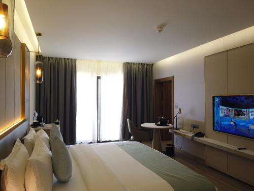 H Luxury Hotel في وادي موسى: غرفة فندق بسرير كبير وتلفزيون