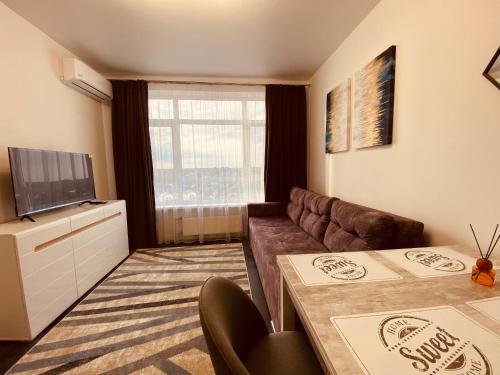 a living room with a couch and a television at DeLight Apartments in Boryspilʼ