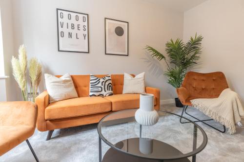 a living room with an orange couch and a glass table at Green Park House, Private Garage and Parking in Coventry