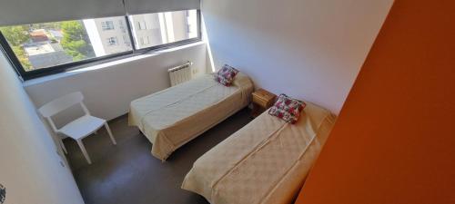 ein kleines Zimmer mit 2 Betten und einem Fenster in der Unterkunft Departamento en el centro de Neuquén Capital in Neuquén