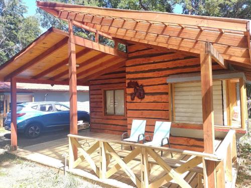 una cabina in legno con tenda da sole e sedie su una terrazza di cabañas anvi pucon a Pucón