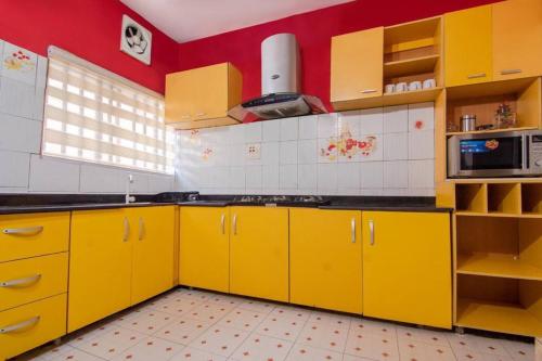 eine Küche mit gelben Schränken und einer roten Wand in der Unterkunft Daffodil Suite in Lagos