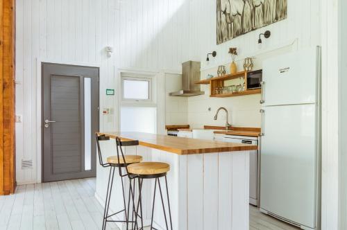 uma cozinha com um frigorífico branco e bancos de bar em BOG Nórdica 2 em Villa La Angostura