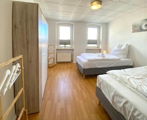 a room with two beds and two windows at Exklusive Monteur-Unterkünfte Apartments, Balkon, Grill, Smart-TV, NETFLIX, Küche in Aschersleben